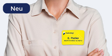 Ein gelbes Namensschild, bedruckt mit einem Namen und einer Firma, klebt auf der Bluse einer Frau