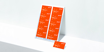 Ein Bogen mit orange bedruckten Einsteckschildern lehnt an einer Wand