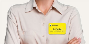 Bedrucktes Namensschild in Gelb, das auf der Bluse einer Frau klebt