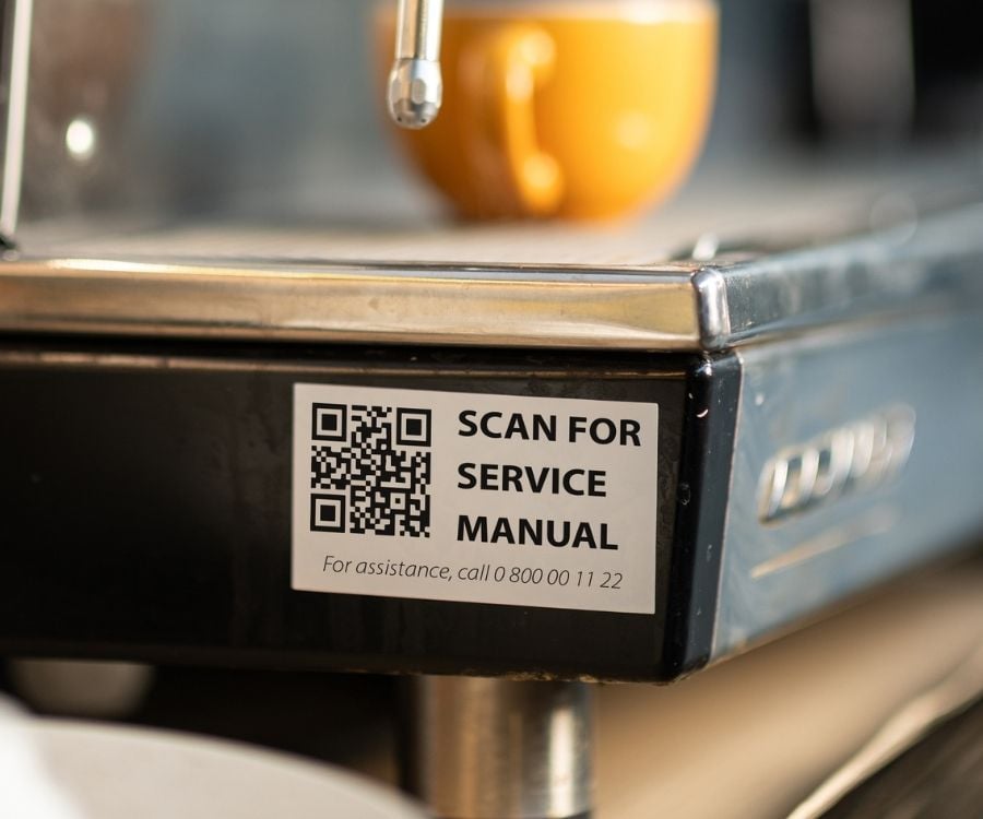 Ein QR Code Aufkleber klebt auf einer Kaffee-Maschine.