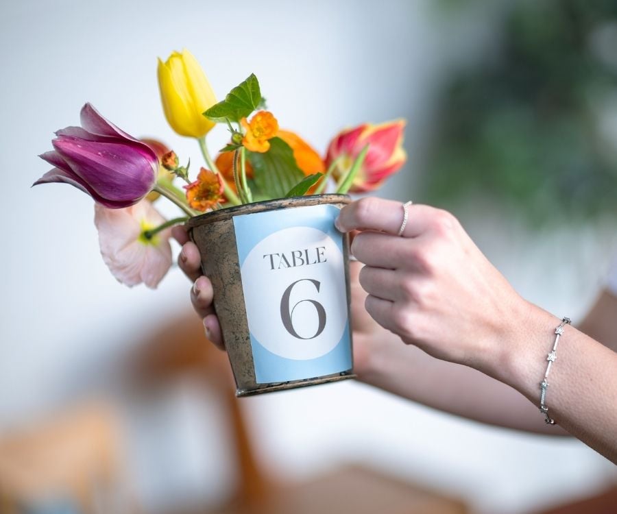 Eine Hand klebt ein Etikett auf einen Blumentopf.