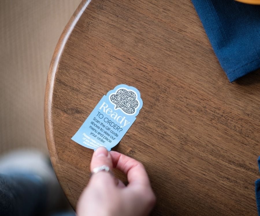Eine Hand klebt einen individuellen Sticker auf den Tisch.