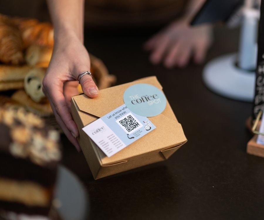 Eine Hand hält ein Paket eines Cafes.