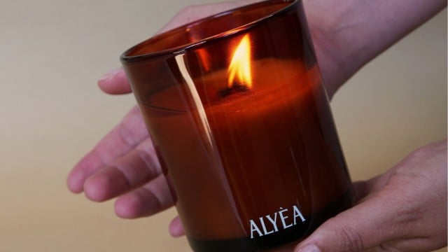 Jemand hält eine brennende ALYEA Kerze in der Hand.
