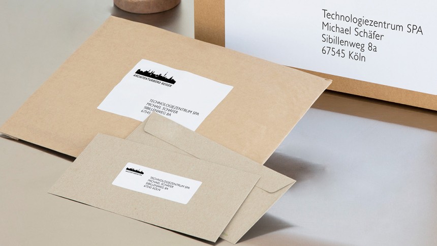 Verschiedene Pakete und Briefe sind nebeneinander aufgereiht. Auf allen kleben Etiketten zur Büroorganisation für den Paketversand.