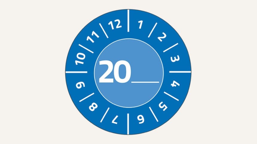 Man sieht eine blaue, runde Prüfplakette. Im Kreis stehen weiße Zahlen von 1 bis 12. In der Mitte steht eine 20 und danach zwei Unterstriche, um die genaue Jahreszahl einzutragen.