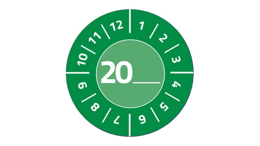 Eine grüne Prüfplakette, kreisrund stehen die Zahlen 1 bis 12. In der Mitte steht 20 und man kann selbst die Jahreszahl eintragen.