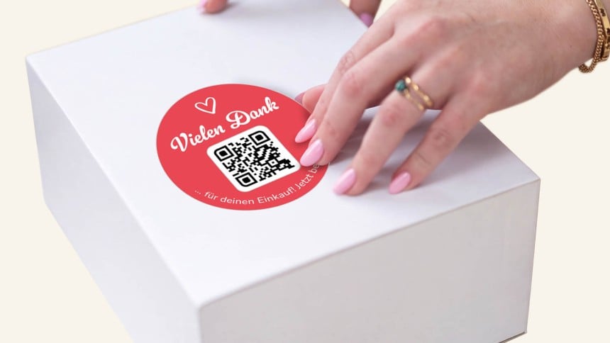 Hand klebt Danke-Sticker auf.