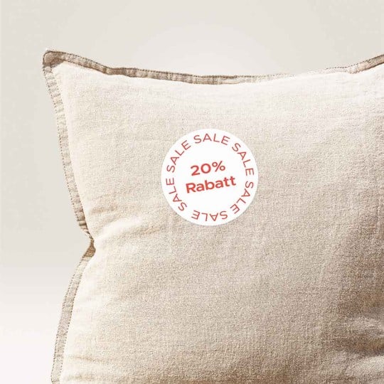 Ein beiges Kissen mit einem 20% Rabatt - Aufkleber in korallrot