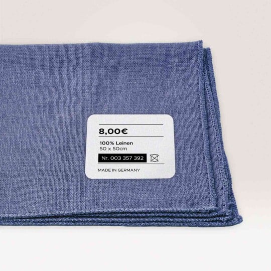 Ein Stoffmuster mit einem Textiletikett, mit Preisangabe Produktnummer und Maßangabe