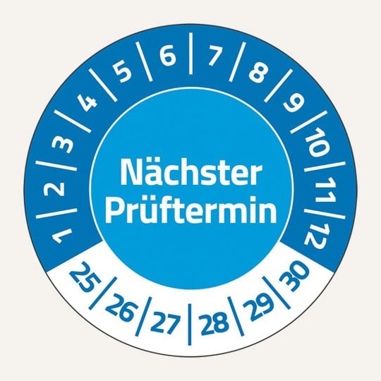 Man sieht eine runde Prüfplakette In der Mitte steht "Nächster Prüftermin". Oben im Halbkreis stehen in Weiß die Zahlen 1 bis 12. Unten stehen die Zahlen 25 bis 30.