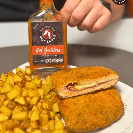 Man sieht Kartoffeln mit Cordon Bleu und eine Saucen-Flasche mit Etikett.