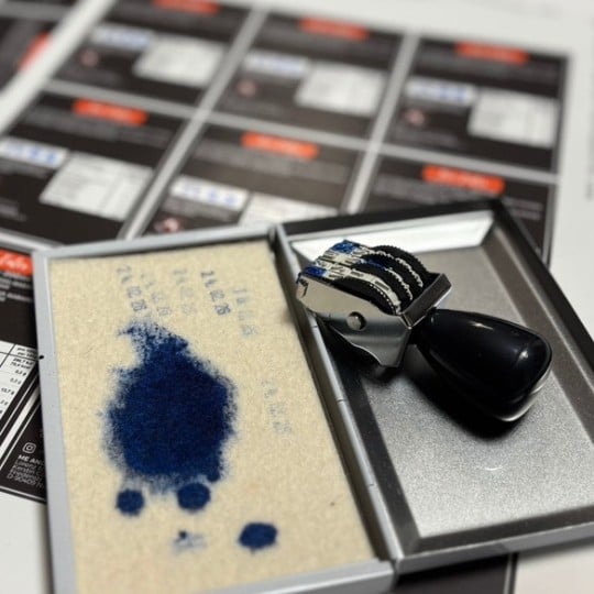 Stempel und Etikettenbögen sind sichtbar. Mit dem Stempel wird das MHD in die Etiketten gedruckt.