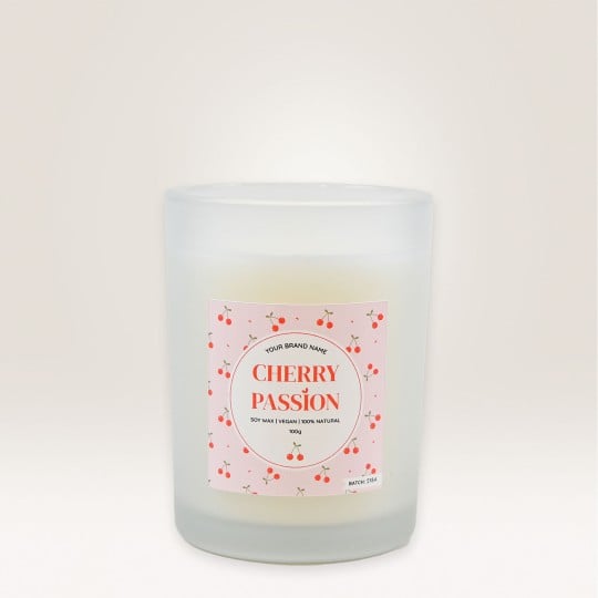 Auf einem Kerzenglas klebt ein Etikett, auf dem Cherry Passion steht und das mit Kirschen verziert ist.