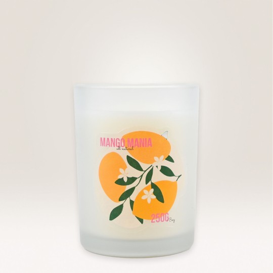 Auf einem Kerzenglas klebt ein Etikett, auf dem Mango Mania steht und mehrere Mangos abgebildet sind.