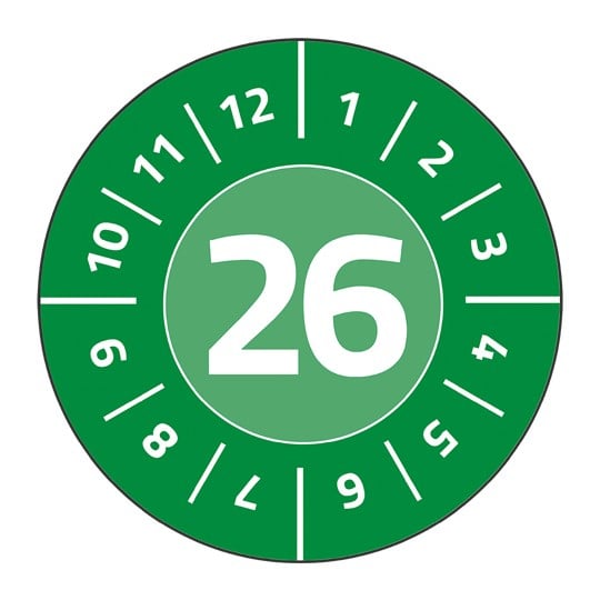 Eine grüne Prüfplakette. In der Mitte steht die Zahl 26 in Weiß. Im Kreis darum stehen die Zahlen 1 bis 12 in Weiß.