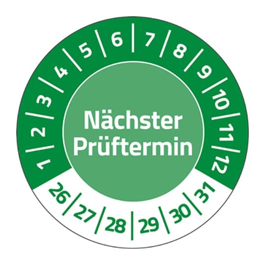 Eine grüne Prüfplakette, in deren Mitte steht "Nächster Prüftermin". Im Halbkreis stehen die Zahlen 1 bis 12. Unten stehen die Zahlen 26 bis 31.