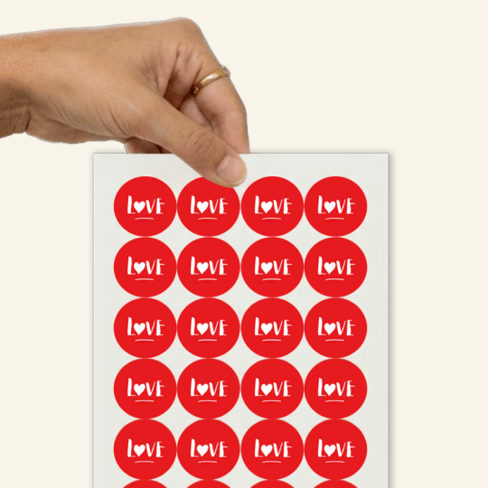 Eine Hand greift einen Bogen mit Aufklebern.