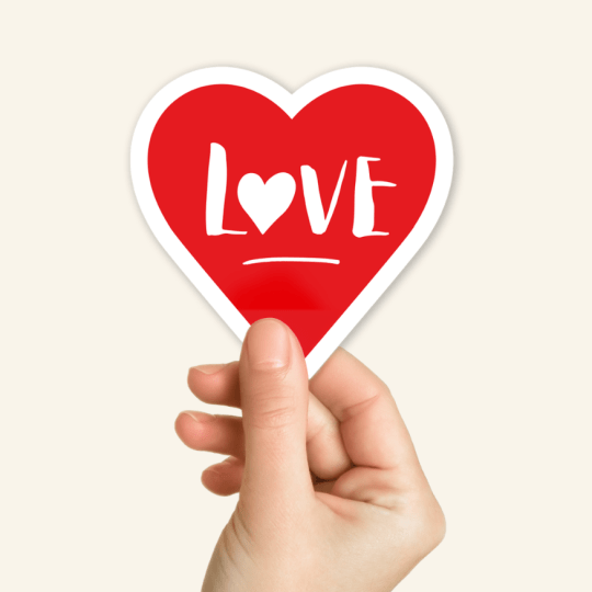 Eine Hand greift einen Einzelsticker aus Herzform.