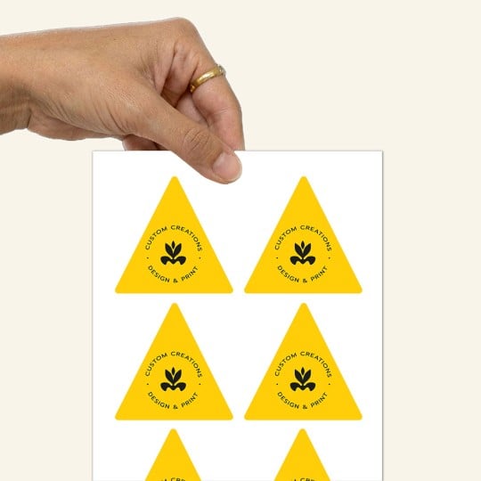 Eine Hand hält einen Bogen mit dreieckigen Aufklebern.