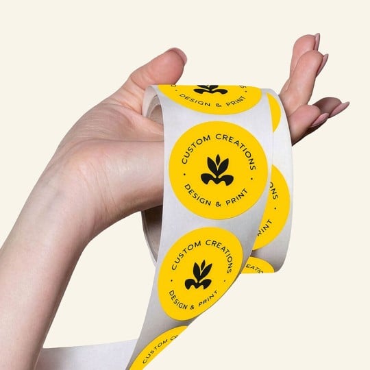 Eine Hand hält eine Rolle mit bedruckten runde Etiketten.