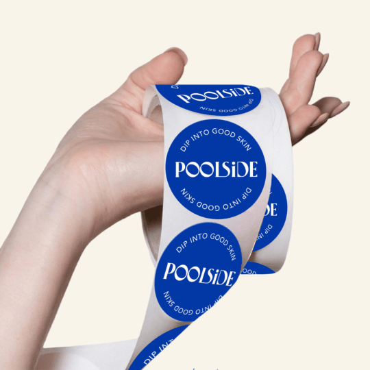 Hand hält eine Rolle mit Etiketten im Sommer Stil. 