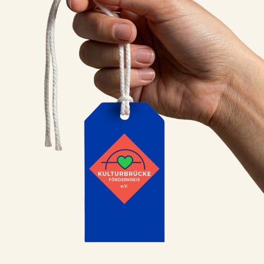 Eine Hand hält einen Produktanhänger mit Vereinslogo.