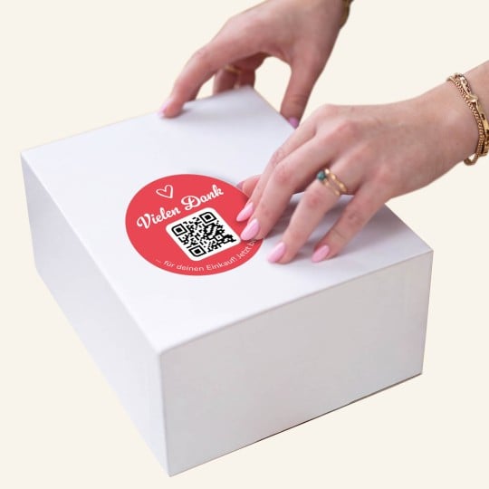Hand klebt Danke-Sticker auf.