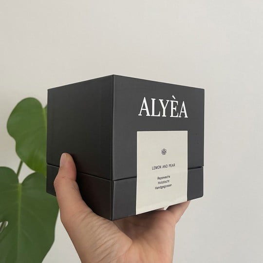 Die Seitenansicht einer Produktverpackung einer ALYEA Kerze.