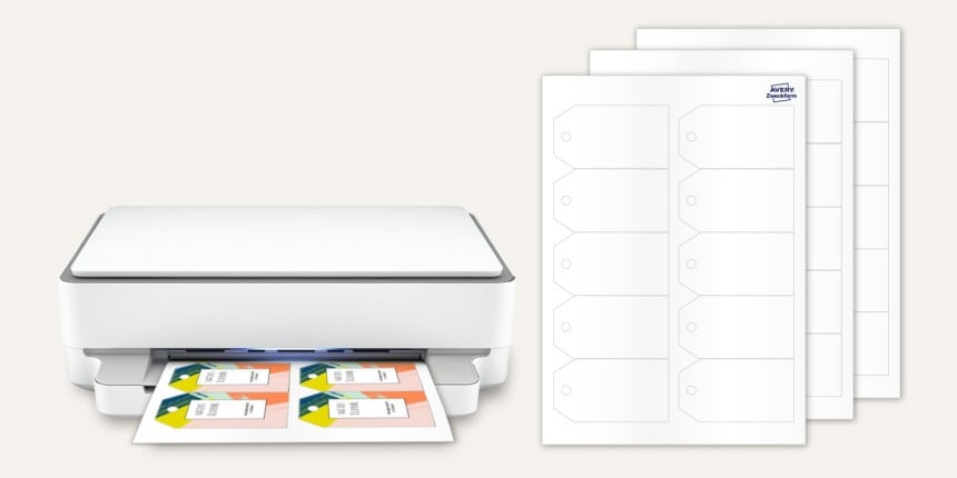 Aus einem Drucker kommen bedruckte Anhänger raus, daneben sind mehrere Bögen von Blanko-Anhänger zum selbst bedrucken zu sehen.