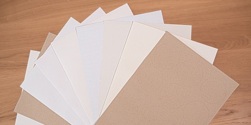 P&M-Bögen aufgefächert A4 Bögen in verschiedenen Materialien liegen aufgefächert auf einer Holzplatte.