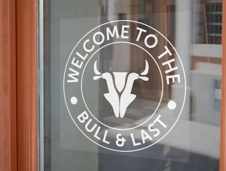 Ein transparenter Fensteraufkleber mit weißer Schrift und weißem Logo klebt an der Tür.