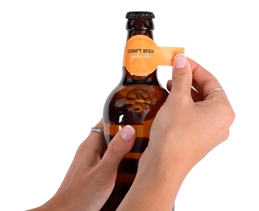 Jemand klebt ein bedrucktes Flügeletikett auf einen Flaschenhals.