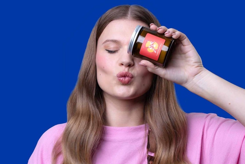 Eine Frau hebt ein Glas in der Hand und zwinkert mit dem Auge.