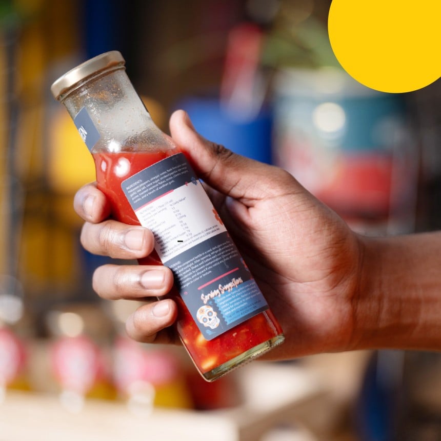Eine Hand hält eine Saucen-Flasche mit einem Rückseitenetikett.
