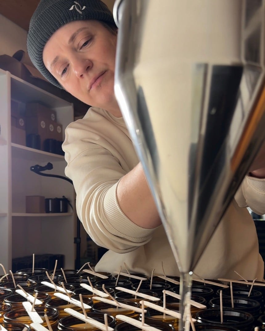 Eine Frau gießt eigene Kerzen und Düfte auf.