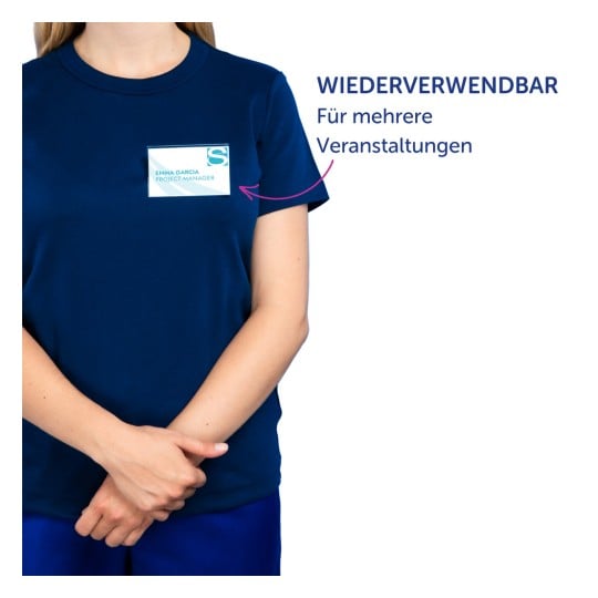 Das Bild zeigt eine Person in einem dunkelblauen T-Shirt mit einem Namensschild, auf dem 'Emma Garcia Project Manager' steht. Der Text an der Seite auf Deutsch lautet 'WIEDERVERWENDBAR' und 'Für mehrere Veranstaltungen,' was darauf hinweist, dass das Namensschild für mehrere Veranstaltungen wiederverwendbar ist.