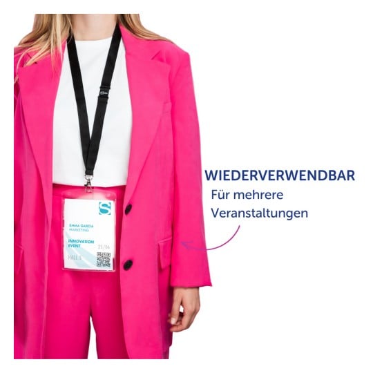 Das Bild zeigt eine Person, die eine leuchtend pinke Anzugjacke und Hose trägt und ein Abzeichen hält, auf dem ihr Name, ihre Rolle und Details zu einer Veranstaltung stehen. Es gibt eine Nachricht, die darauf hinweist, dass das Abzeichen für mehrere Veranstaltungen wiederverwendbar ist.