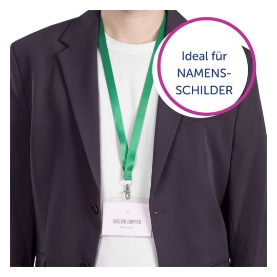 Eine Person trägt einen dunklen Blazer und ein weißes Hemd, mit einem grünen Schlüsselband, an dem ein Namensschild hängt, auf dem 'MELVIN DOPPER, Designer' steht.