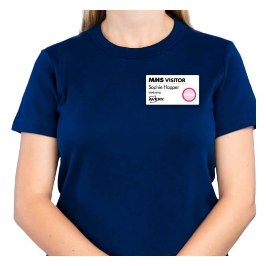 Das Bild zeigt eine Person, die ein marineblaues T-Shirt trägt und einen Besucher-Ausweis mit der Aufschrift 'MHS VISITOR', 'Sophie Hopper' und 'Marketing'. Der Ausweis enthält ein 'VOID'-Label.
