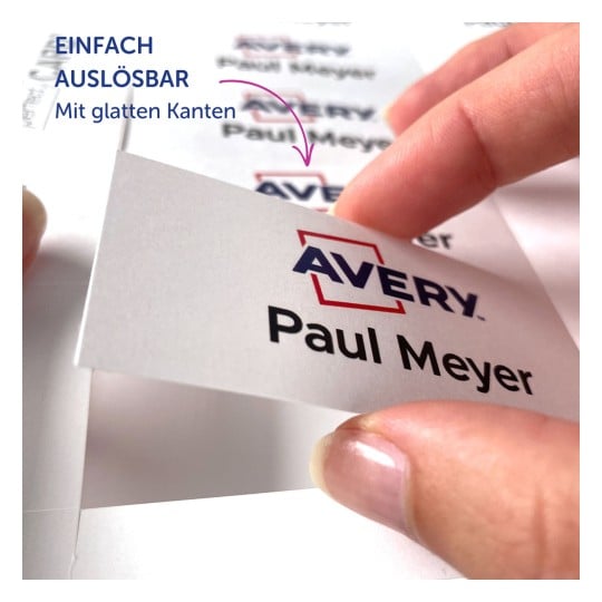 Das Bild zeigt eine Hand, die ein Etikett mit dem Namen 'Paul Meyer' und der Marke 'Avery' hält, zusammen mit einem Text, der darauf hinweist, dass es leicht zu entfernen ist und glatte Kanten hat.