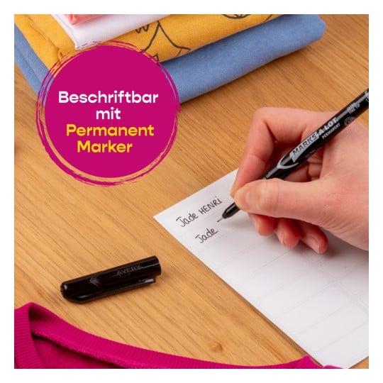 Ein Bild zeigt eine Hand, die mit einem Permanentmarker auf ein Etikett schreibt, umgeben von gefalteten Hemden und einer schwarzen Markerkappe.