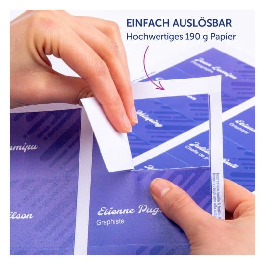 Das Bild zeigt eine Hand, die ein Etikett von einem Bogen Qualitäts-Papier abzieht, der blaue und violette Designs mit aufgedruckten Namen zeigt. Die Etiketten lassen sich leicht abziehen.