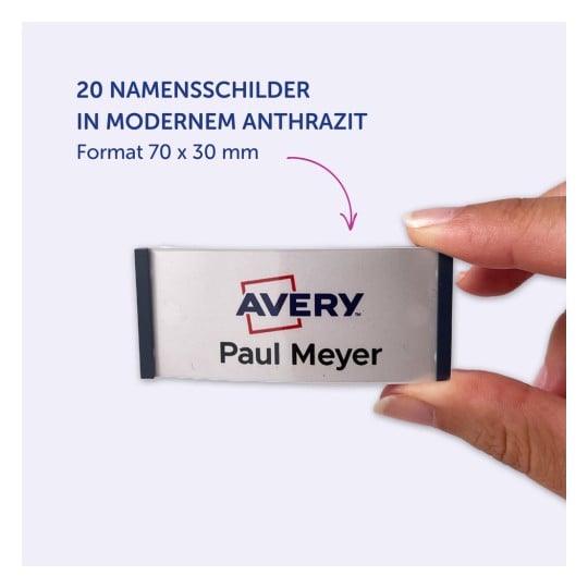 Das Bild zeigt ein Namensschild von Avery, mit dem Namen 'Paul Meyer' und hervorgehobenen Details auf Deutsch über ein Set von 20 Namensschildern in modernem Anthrazit, Größe 70 x 30 mm.