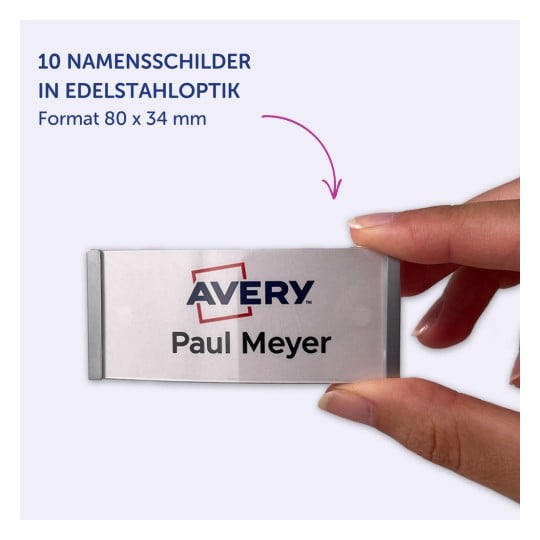 Das Bild zeigt eine Person, die ein Namensschild mit der Aufschrift 'Avery Paul Meyer' hält. Das Abzeichen ist silberfarben mit einer Plastikabdeckung und misst 80 x 34 mm.
