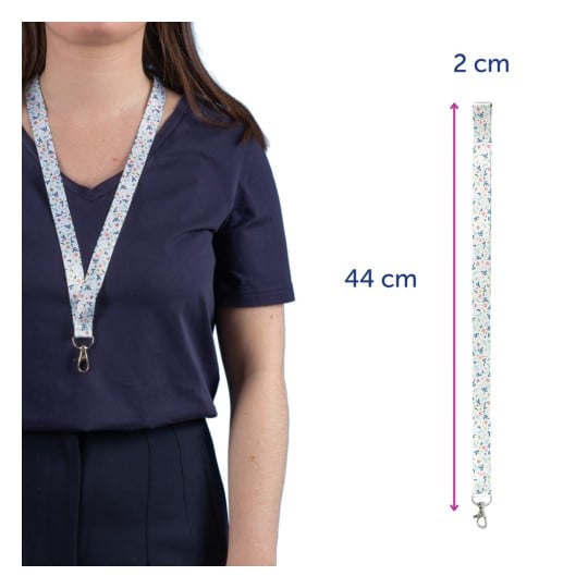Das Bild zeigt eine Frau, die ein florales Schlüsselband um den Hals trägt. Das Schlüsselband ist 44 cm lang und 2 cm breit, mit einem Karabinerhaken am Ende.