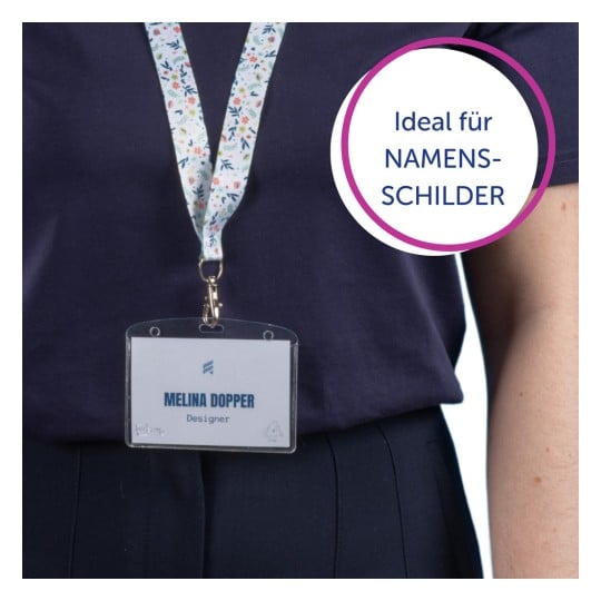 Das Bild zeigt eine Person, die ein dunkles Oberteil trägt und einen Schlüsselband mit einem Namensschild hält, auf dem 'MELINA DOPPER, Designer' steht. Es gibt eine kreisförmige Grafik mit der Aufschrift 'Ideal für NAMENSSCHILDER'.