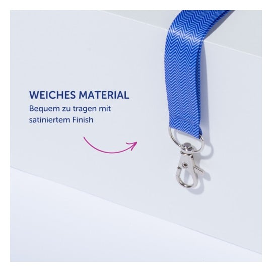 Das Bild zeigt ein blaues Schlüsselband aus weichem Material, das seine Bequemlichkeit und satinierte Oberfläche hervorhebt. Daneben befindet sich ein Text auf Deutsch, der seine Merkmale beschreibt.