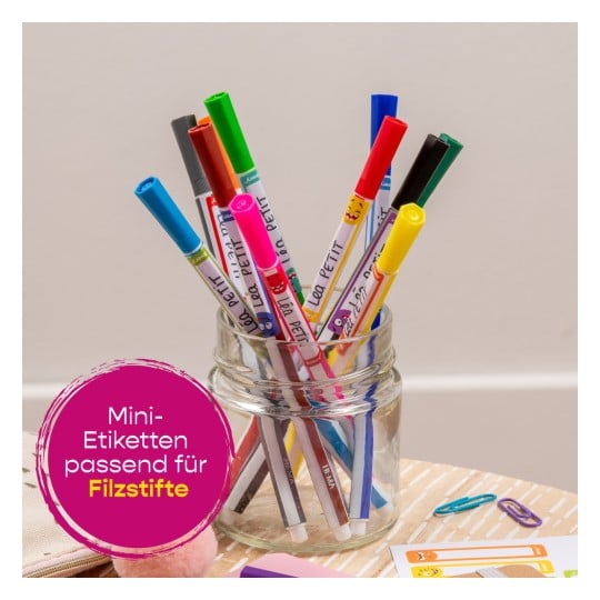 Das Bild zeigt ein Glas, das mit bunten Markern gefüllt ist, darunter verschiedene leuchtende Farbtöne und Designs. Es gibt ein rundes Etikett mit der Aufschrift 'Mini-Etiketten passend für Filzstifte'.