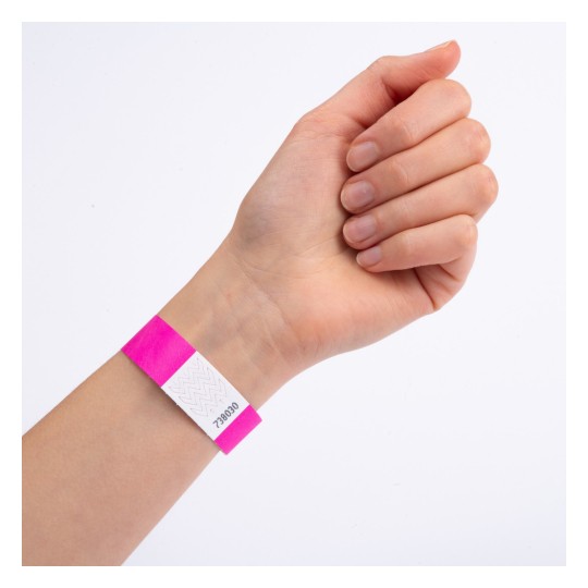 Das Bild zeigt eine Hand mit einem rosa Armband, das einen weißen Abschnitt mit einer Nummer aufweist.